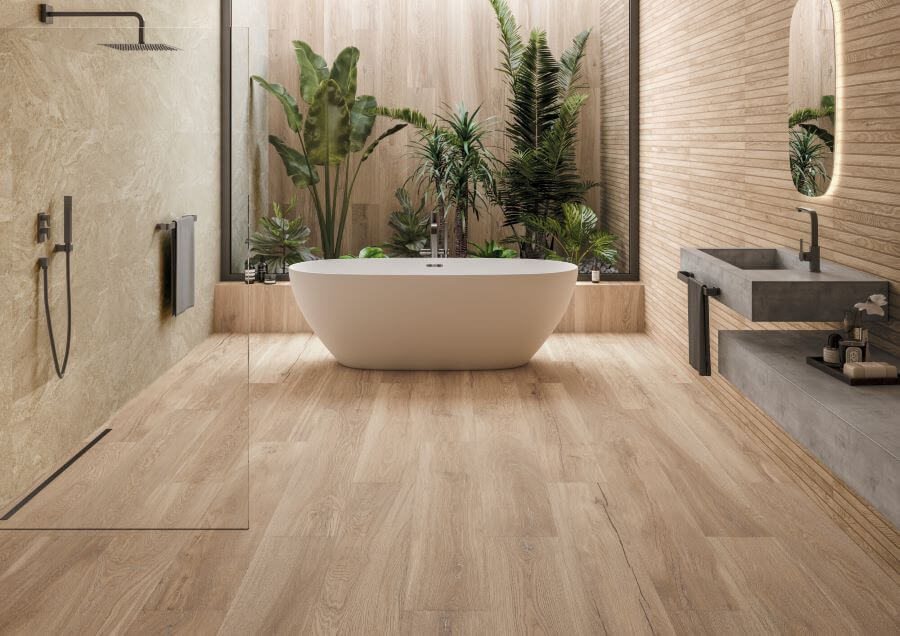 SEASON-CARAMEL-OAK-WOOD-EFFECT-PORCELAIN-TILES. Image shows caramel oak wood effect porcelain tiles in bathroom with bath and foliage in background