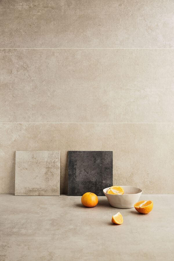 BEAT-BEIGE-ANTHRACITE-CLOSE-UP. Image shows close up of beige tiles with small anthracite sample and some oranges