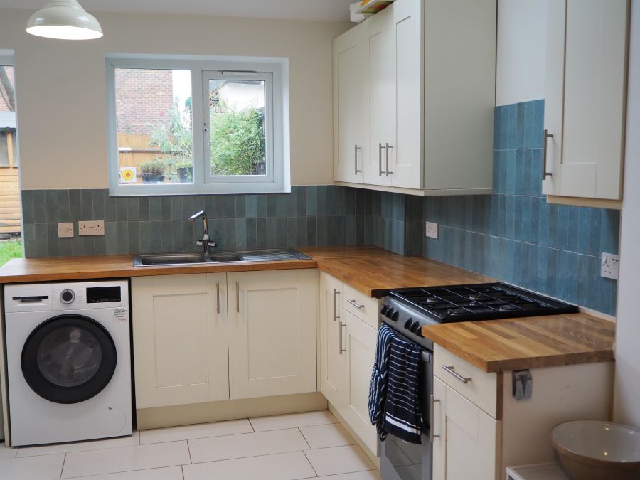 ADORE-AQUA. Image shows blue feature tiles to walls in kitchen with white kitchen cabinets and wooden work surface