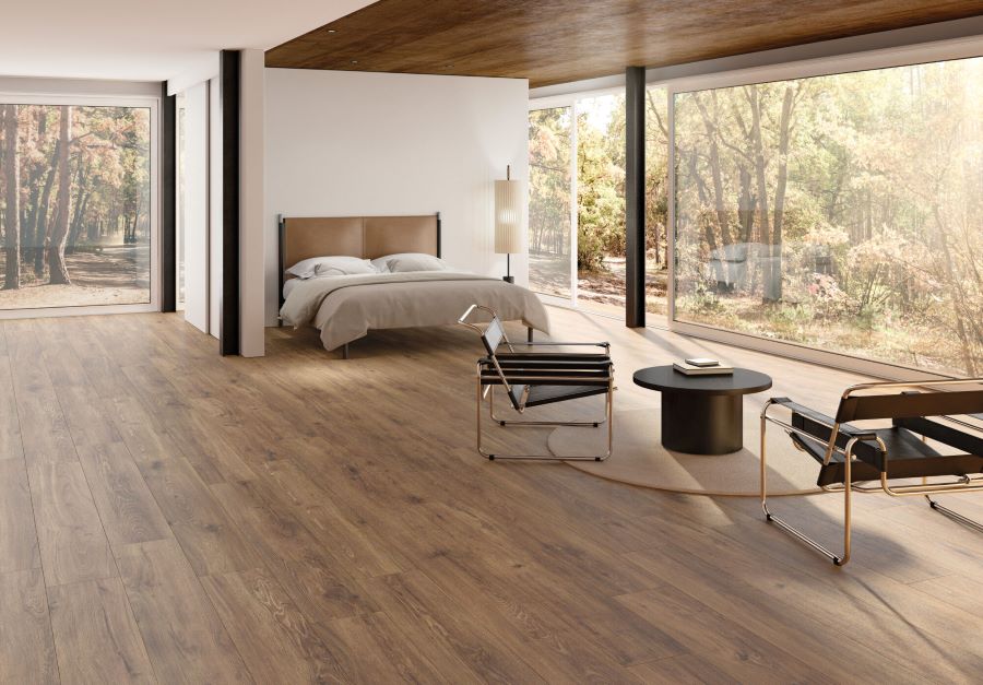 SERENITY-SIENNA-WOOD-PLANK-PORCELAIN-TILE. Image shows dark brown wood plank porcelain tile on floor of bedroom.