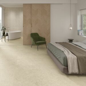 SWOOP-BEIGE-PORCELAIN-FLOOR-TILE. Image shows beige porcelain tile on floor of bedroom with bed and green chair