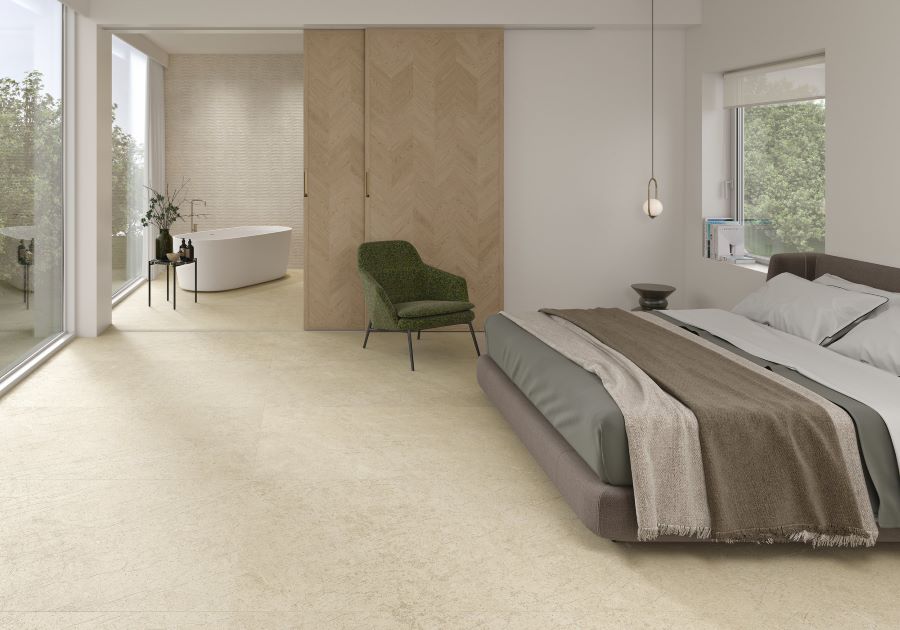 SWOOP-BEIGE-PORCELAIN-FLOOR-TILE. Image shows beige porcelain tile on floor of bedroom with bed and green chair