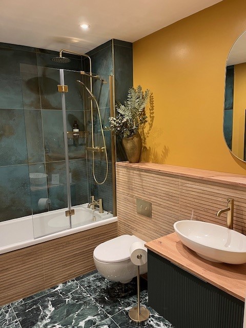 FORGE-MINT-METALLIC-PORCELAIN-TILE. Image shows mint green metallic tile behind bath with yellow wall and wooden vanity.