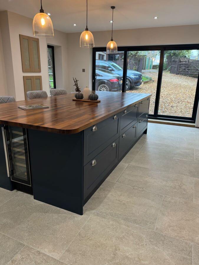 4A. Image shows tiled kitchen floor with taupe stone effect tiles and a navy blue kitchen unit with wooden worktops