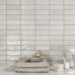 White Adore White ceramic Spanish tiles displayed on a wall with towels and soap.