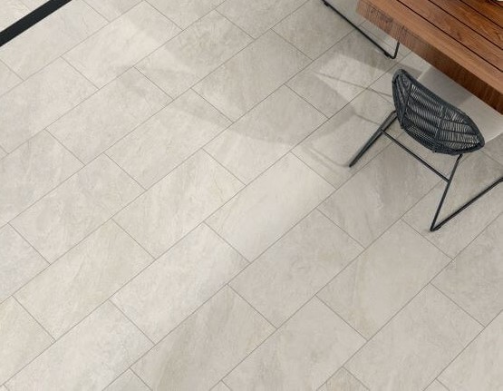 ALPINE-CHAMPAGNE-QUARTZ-EFFECT-PORCELAIN-TILE-OUTSIDE. Image shows off-white quartz effect porcelain tile on patio with wood table and charcoal chiars
