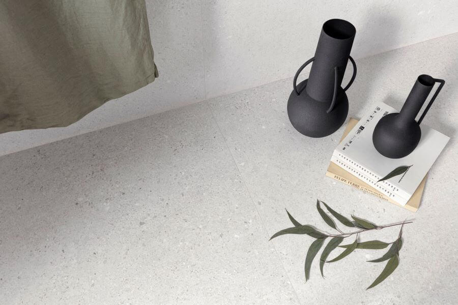DEFINE-WHITE-TERRAZZO-EFFECT-PORCELAIN-TILES. Image shows white terrazzo effect porcelain tile close up with flasks and books