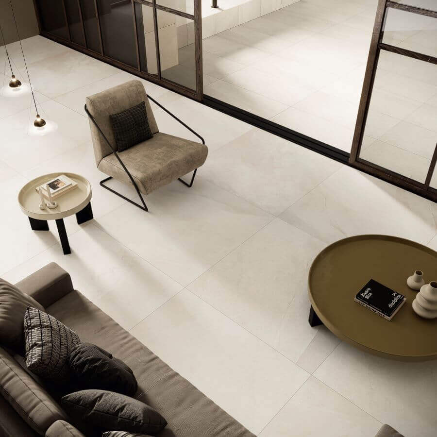 ETHOS-SHORE-STONE-LOOK-PORCELAIN-TILE. Image shows cream stone look porcelain tile in a lounge with a sofa, chair and table