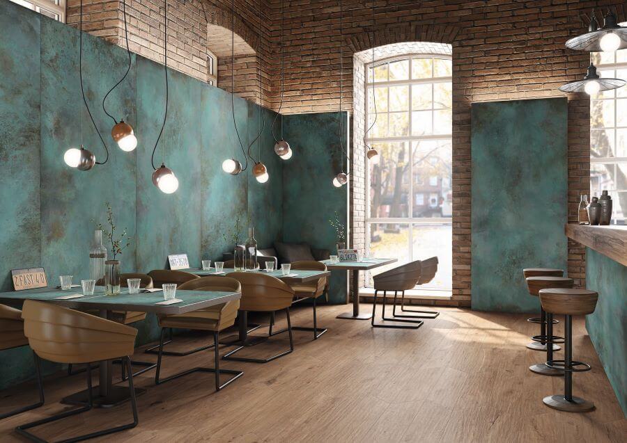 FORGE-MINT-PORCELAIN-METALLIC-TILES. Image shows green metallic tiles on walls of restaurant with tables and chairs