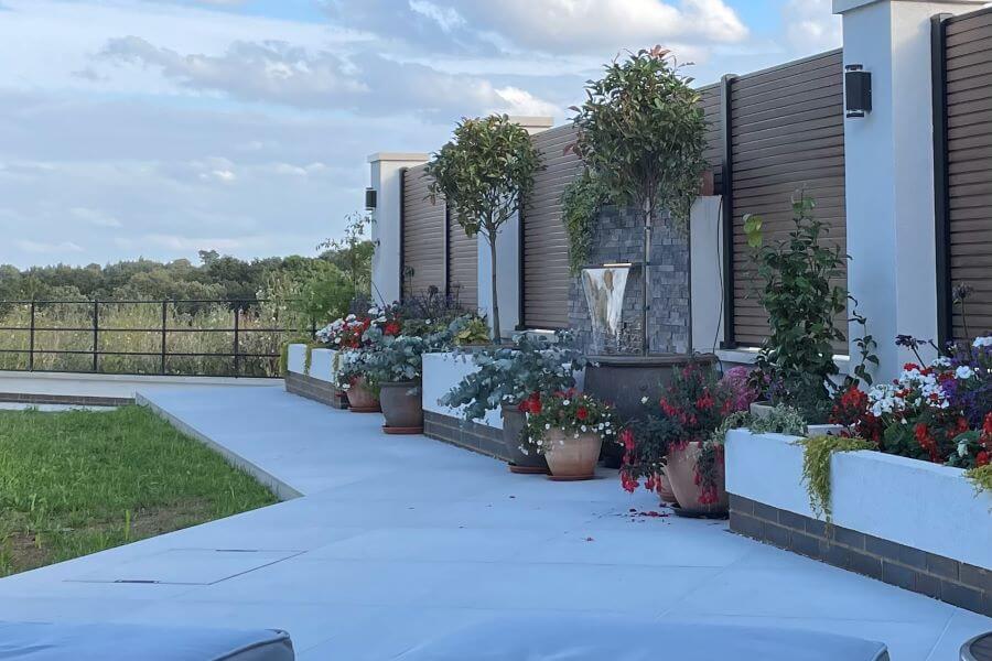 POISE-PEBBLE-PAVERS. Image shows 2cm light taupe porcelain paver to patio with flowerbeds