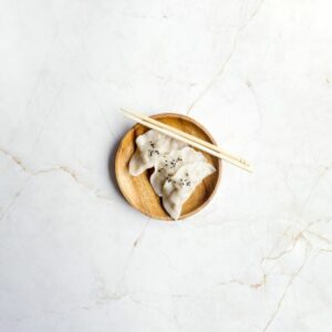JEWEL-MARBLE-EFFECT-PORCELAIN-TILE-CLOSEUP. Image shows white marble effect porcelain tile with nutmeg veins with plate and food