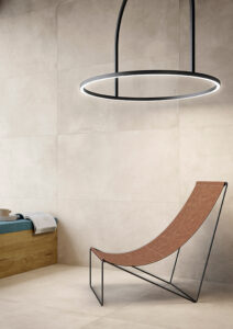 STRIDE-ELEMENT-CONCRETE-LOOK-PORCELAIN-TILE. Image shows light concrete look porcelain tile to wall and floor with chair