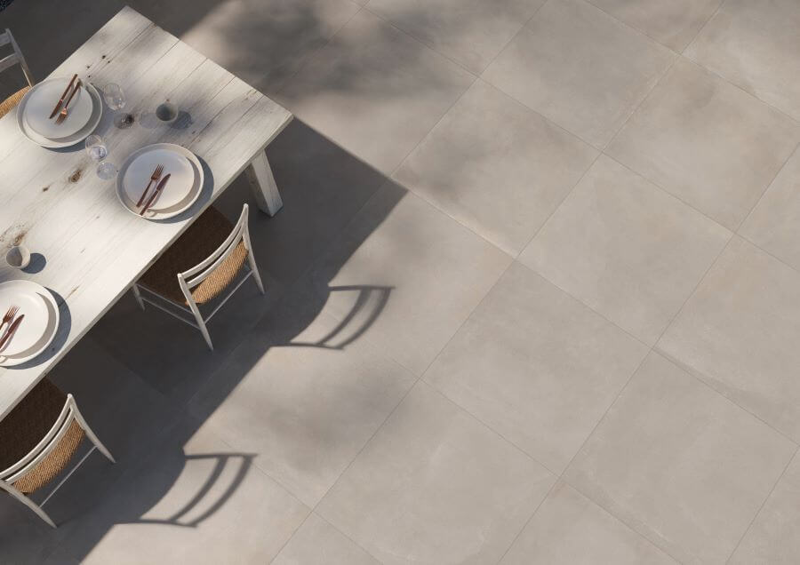 TONE-CONCRETE-2CM-OUTSIDE-PORCELAIN-PAVER. Image shows light brown concrete 2cm outside porcelain paver with a table and chairs