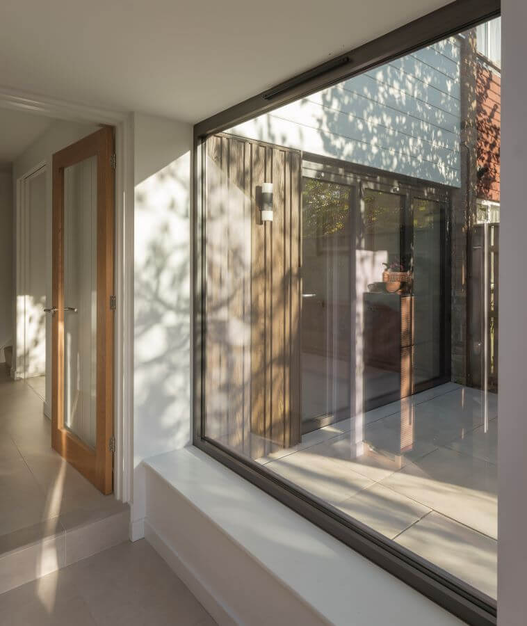 Image shows large window in with view onto patio outside
