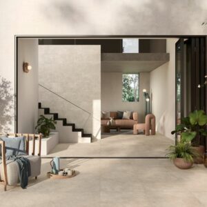 Image shows Minima concrete effect porcelain outdoor tiles in sand on patio with plants and chair looking into lounge
